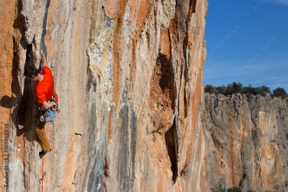 Young male climber hanging by a cliff. Young male climber hanging by a cliff.
