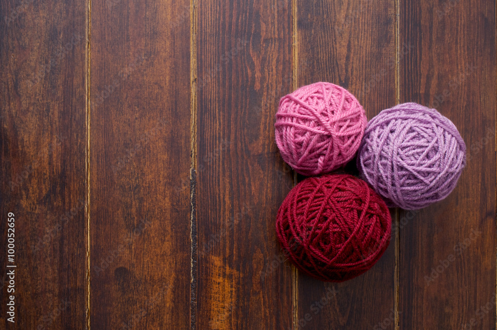 Three skeins in red and pink tones over wooden background Three skeins in red and pink tones over wooden background