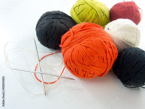 multi color balls of wool and knitting needles over white background 