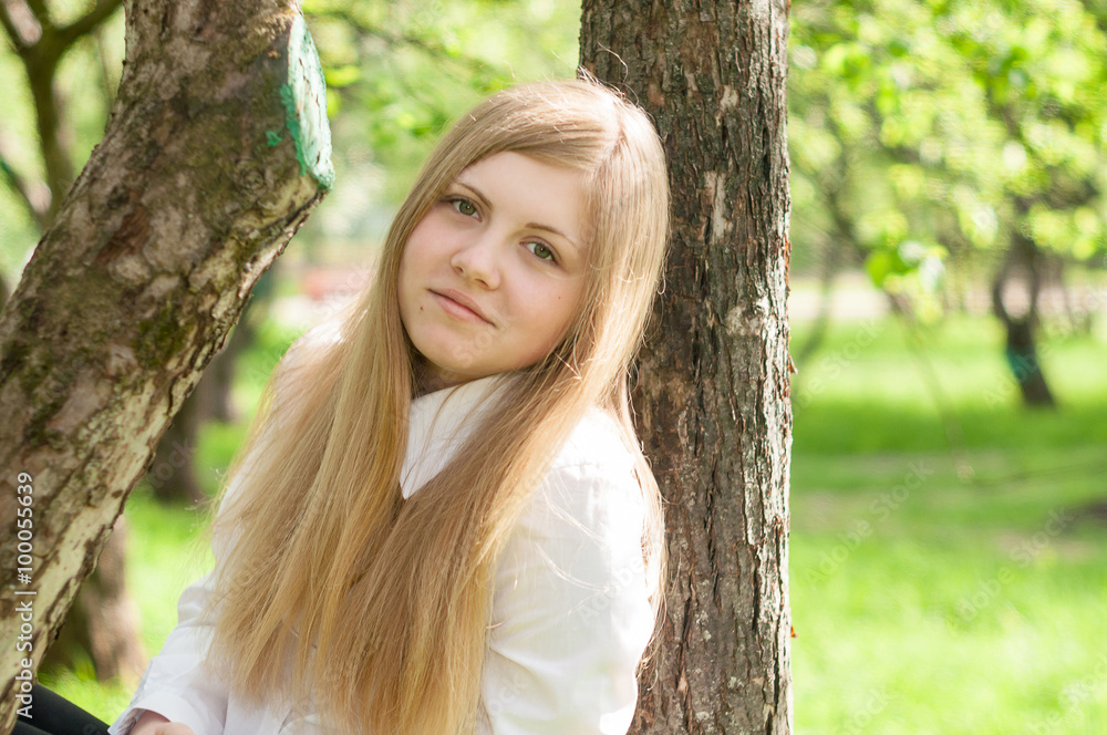 Young girl posing near the tree in a lush garden in the summer Young girl posing near the tree in a lush garden in the summer