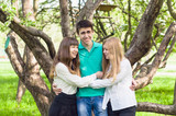 Three happy young friends hugging and laughing in the summer park
