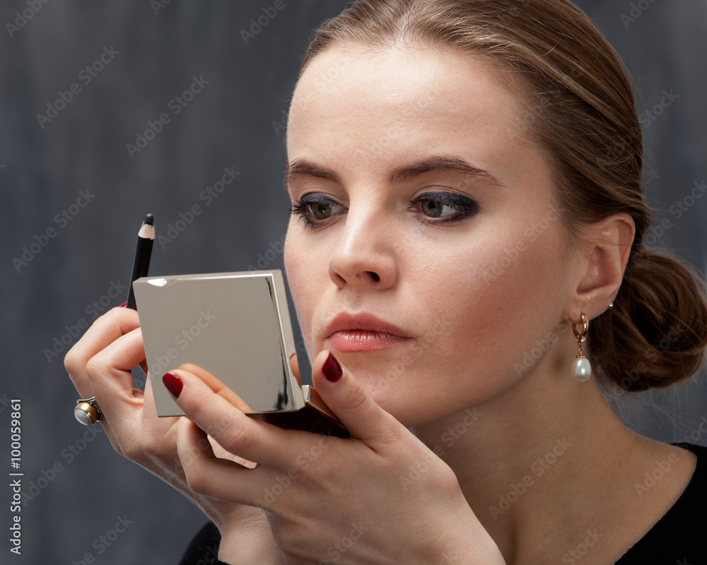 Young woman applying makeup on the eye with eyeliner Young woman applying makeup on the eye with eyeliner
