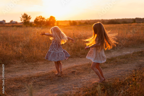 две девочки сестры танцуют,кружатся на закате в поле