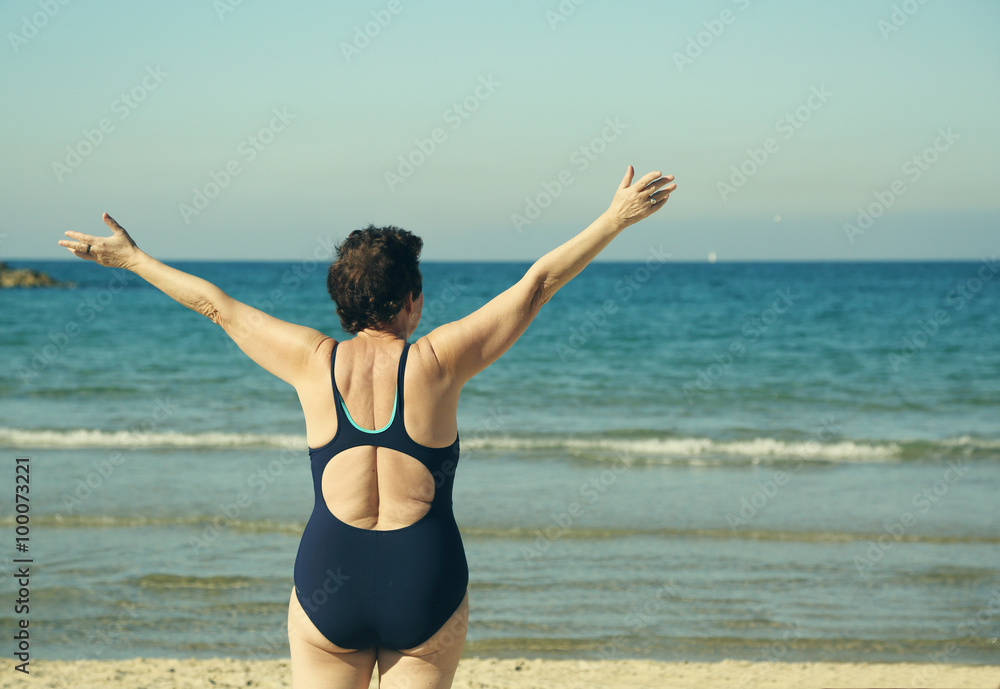 Senior woman standing with open arms over sky background Senior woman standing with open arms over sky background