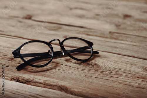 black reading glasses on wooden background