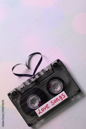 Audio cassette with magnetic tape in shape of hearts on light background