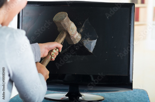 Fotografie Female holding hammer smashing it into computer screen