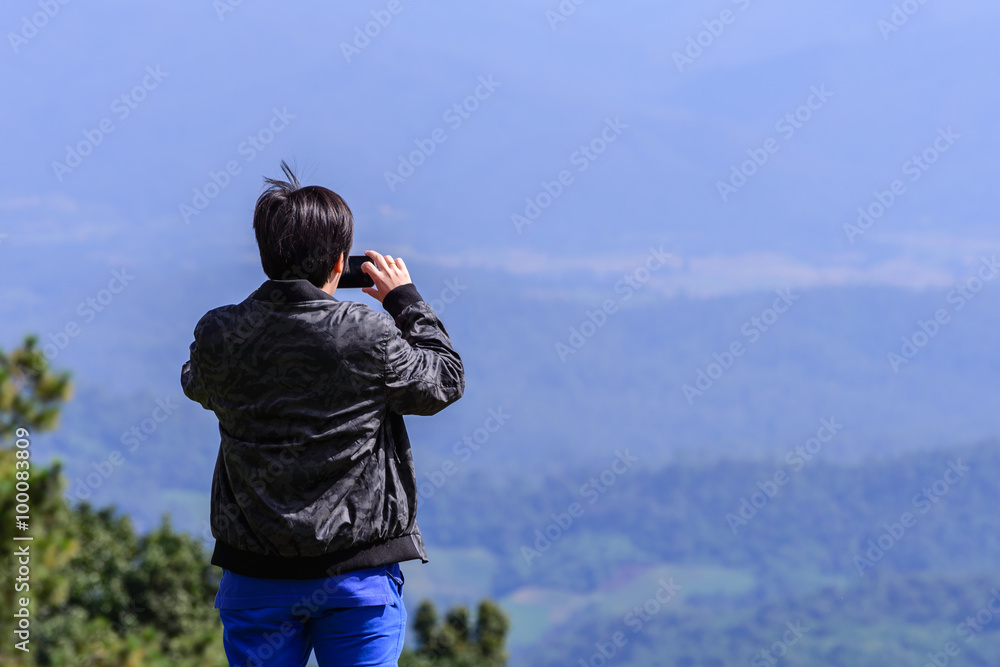Fototapeta premium Man hiker take a photo of mountain view with smartphone.