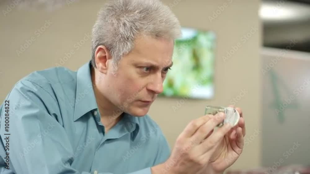 Older customer at a recreational marijuana shop looking closely at a product in a container Older customer at a recreational marijuana shop looking closely at a product in a container