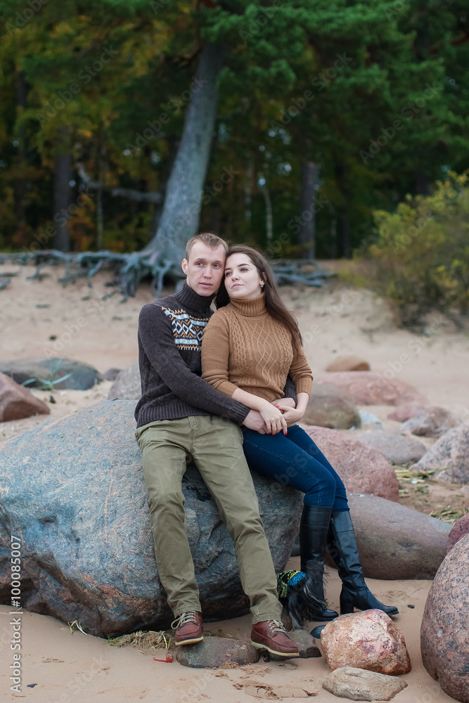 young couple sitting on a rock on the beach