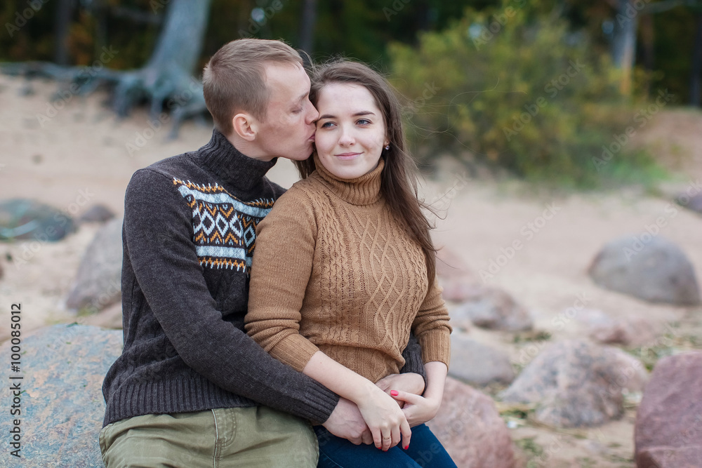young couple sitting on a rock on the beach young couple sitting on a rock on the beach