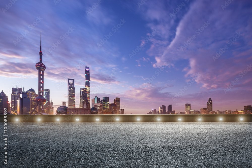 empty asphalt road and cityscape in colorful sky at dawn