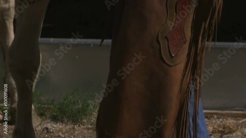 Slow tilt shot of a cowboy petting a skewbald horse