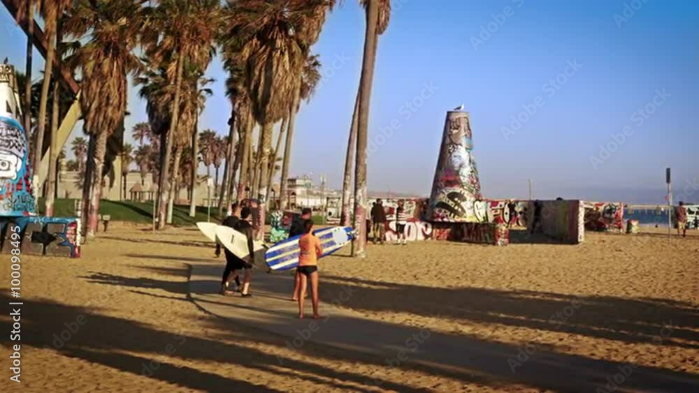 Slow motion shot of three surfers carrying surfboards walking near Venice Beach, California Slow motion shot of three surfers carrying surfboards walking near Venice Beach, California