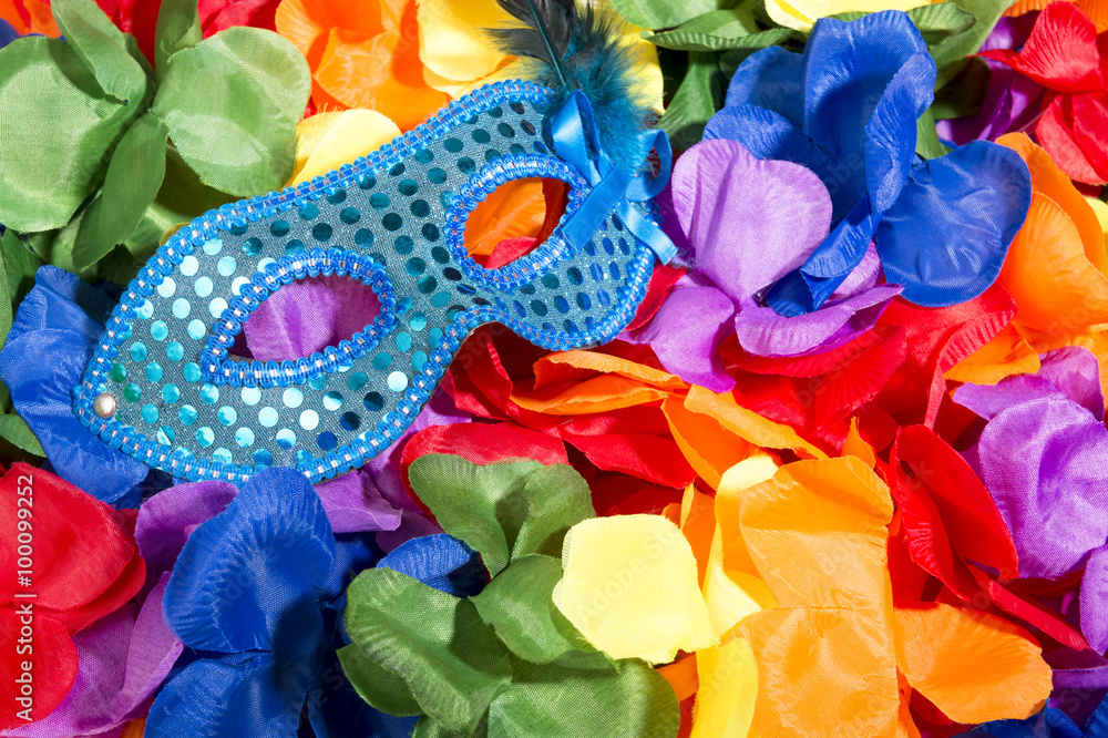 Sparkly carnival mask sitting on brightly colored background of flower leis