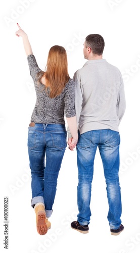 young couple pointing at wal Back view (woman and man). .