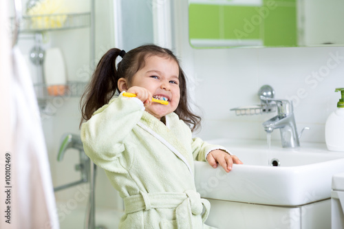 Smiling little girl brushin...
