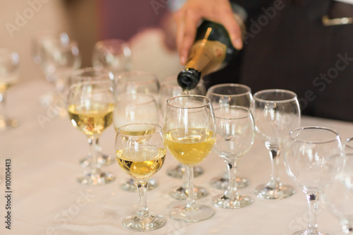 Pouring champagne in flutes standing on table