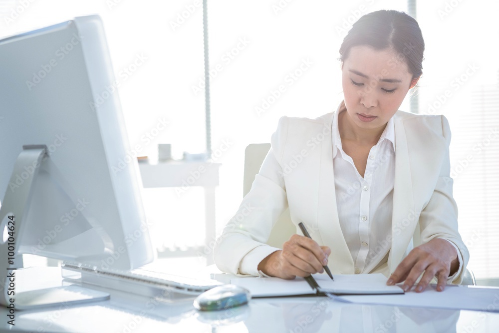 Businesswoman writing on diary on desk Businesswoman writing on diary on desk