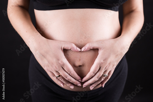 Wallpaper Mural Pregnant Woman holding her hands in a heart shape on her baby bump Torontodigital.ca