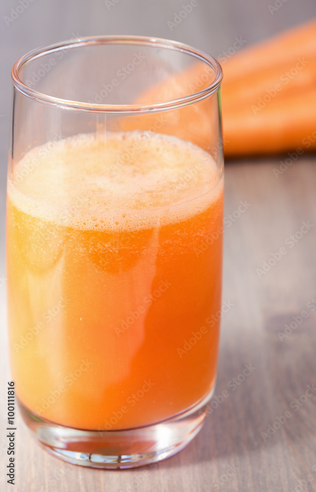 Healthy carrot smoothie in a glass and raw carrots on a wooden background Healthy carrot smoothie in a glass and raw carrots on a wooden background
