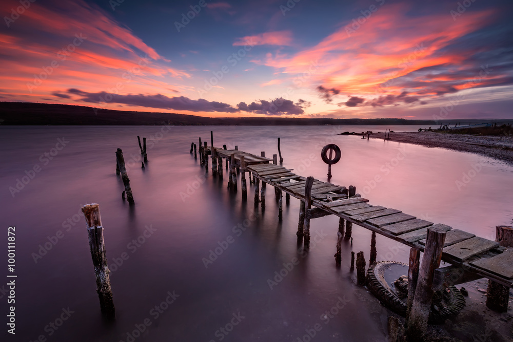 Lake sunset. Magnificent long exposure lake sunset with an old wooden pier.