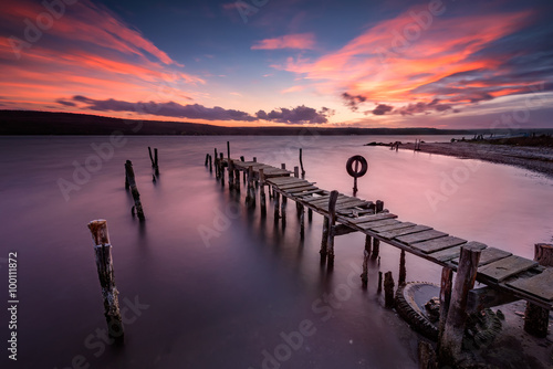 Lake sunset. Magnificent long exposure lake sunset with an old wooden pier.