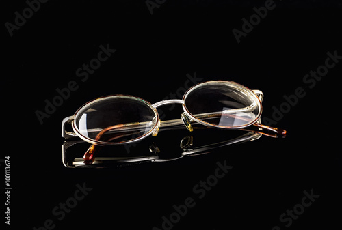 Retro reading glasses on black mirror background