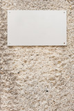 Ein weisses unbeschriftetes Schild auf einer verputzten Wand