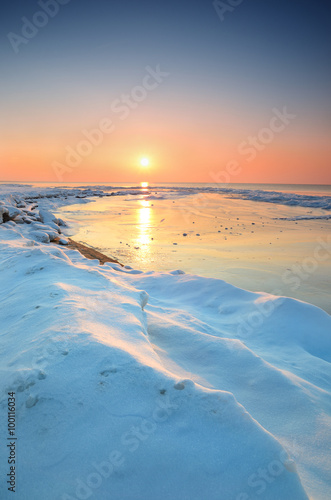 colorful sunset at the snowy Baltic sea shore