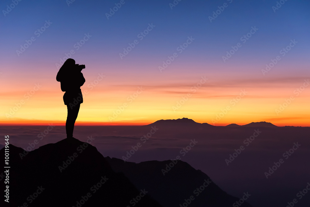 silhouette of woman taking photograph on the top of mountain and silhouette of woman taking photograph on the top of mountain and
