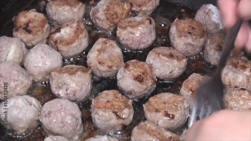 Woman turns over home made meatballs being cooked on the pan. Close up. Woman turns over home made meatballs being cooked on the pan. Close up.