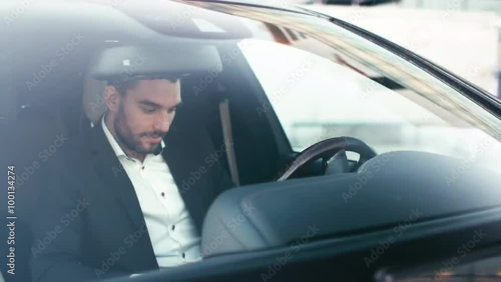Businessman using tablet while sitting inside an executive black car. Shot on RED Cinema Camera. Businessman using tablet while sitting inside an executive black car. Shot on RED Cinema Camera.