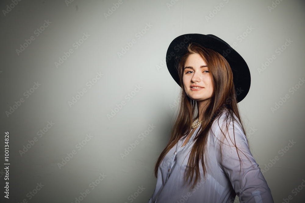 Awesome Caucasian attractive shy sexy female model with brunette hair posing on table in studio, wearing formal suit and hat, isolated on white background Awesome Caucasian attractive shy sexy female model with brunette hair posing on table in studio, wearing formal suit and hat, isolated on white background