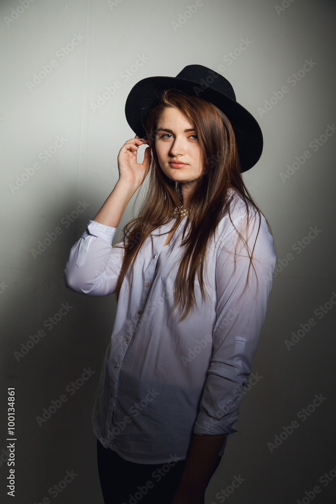 Awesome Caucasian attractive shy sexy female model with brunette hair posing on table in studio, wearing formal suit and hat, isolated on white background Awesome Caucasian attractive shy sexy female model with brunette hair posing on table in studio, wearing formal suit and hat, isolated on white background