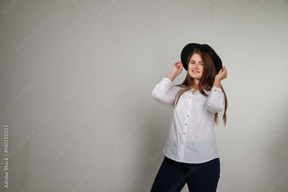 Awesome Caucasian attractive shy sexy female model with brunette hair posing on table in studio, wearing formal suit and hat, isolated on white background Awesome Caucasian attractive shy sexy female model with brunette hair posing on table in studio, wearing formal suit and hat, isolated on white background
