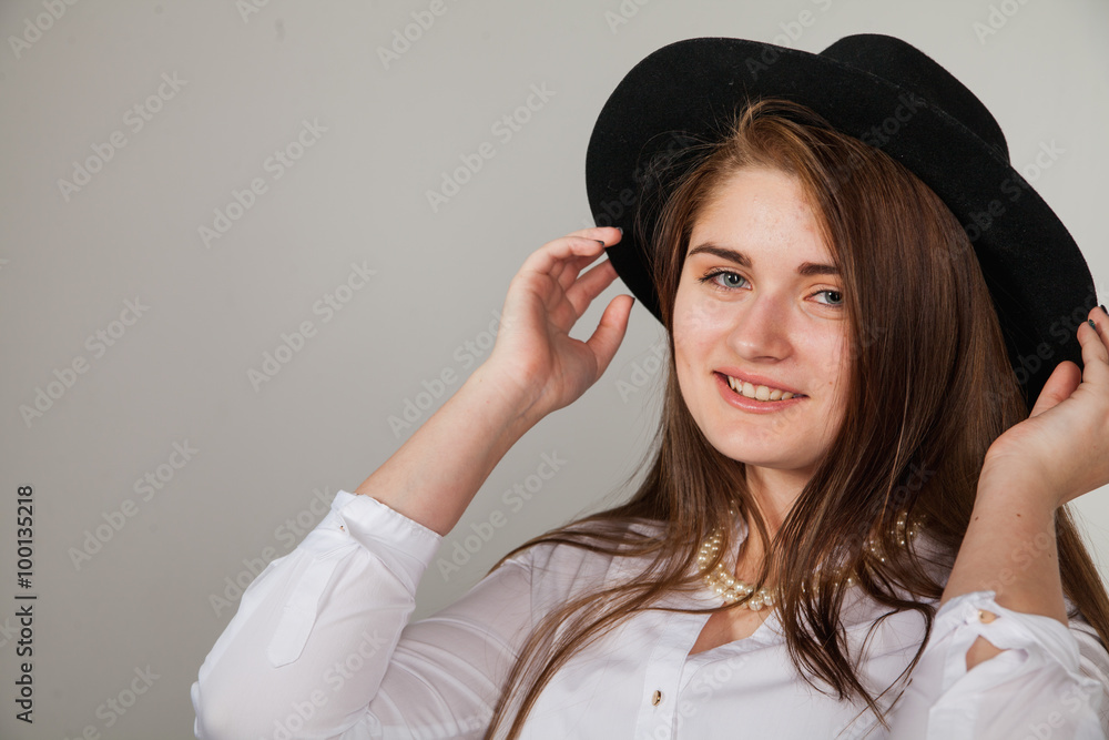 Awesome Caucasian attractive shy sexy female model with brunette hair posing on table in studio, wearing formal suit and hat, isolated on white background Awesome Caucasian attractive shy sexy female model with brunette hair posing on table in studio, wearing formal suit and hat, isolated on white background