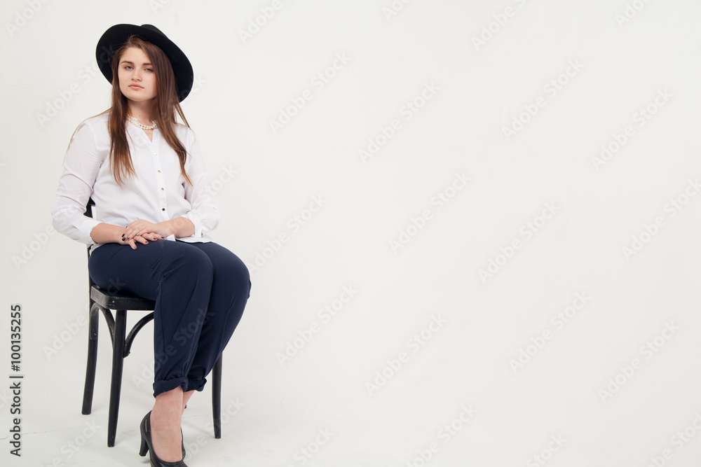 Awesome Caucasian attractive shy sexy female model with brunette hair posing on table in studio, wearing formal suit and hat, isolated on white background Awesome Caucasian attractive shy sexy female model with brunette hair posing on table in studio, wearing formal suit and hat, isolated on white background