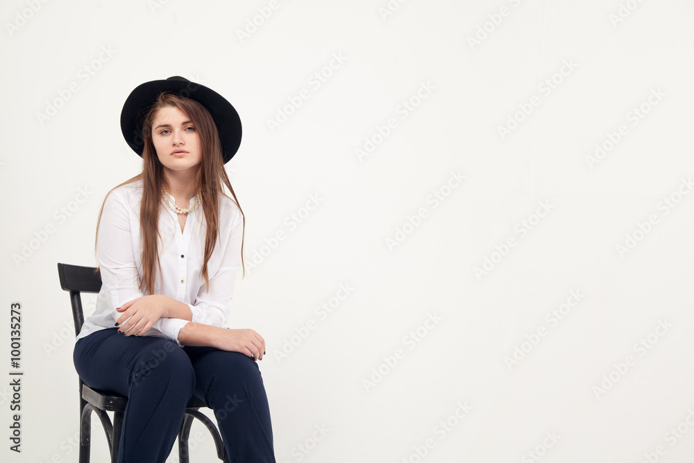 Awesome Caucasian attractive shy sexy female model with brunette hair posing on table in studio, wearing formal suit and hat, isolated on white background Awesome Caucasian attractive shy sexy female model with brunette hair posing on table in studio, wearing formal suit and hat, isolated on white background