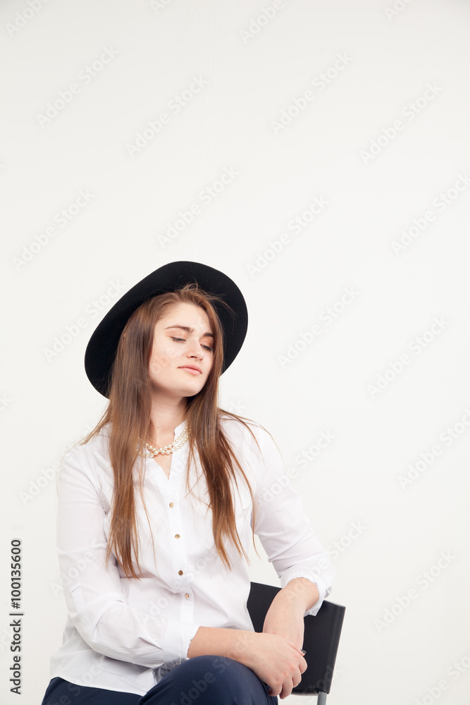 Awesome Caucasian attractive shy sexy female model with brunette hair posing on table in studio, wearing formal suit and hat, isolated on white background Awesome Caucasian attractive shy sexy female model with brunette hair posing on table in studio, wearing formal suit and hat, isolated on white background