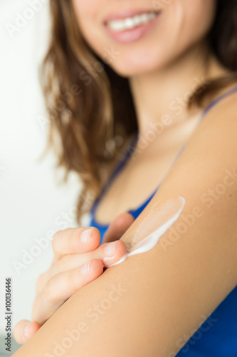 Woman applying body lotion