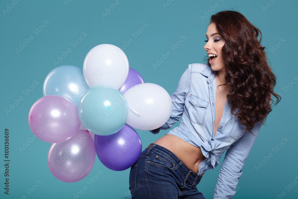 Happy young woman standing over blue wall and holding pink and w Happy young woman standing over blue wall and holding pink and w