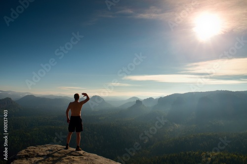 Naked man in black pants only at top of mountain at Sunset.