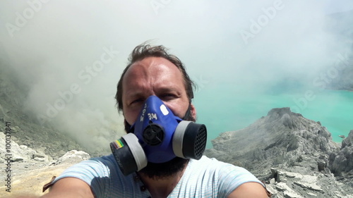 Man in gas mask taking selfie photo, video by Ijen volcano in Java, Indonesia, slow motion
