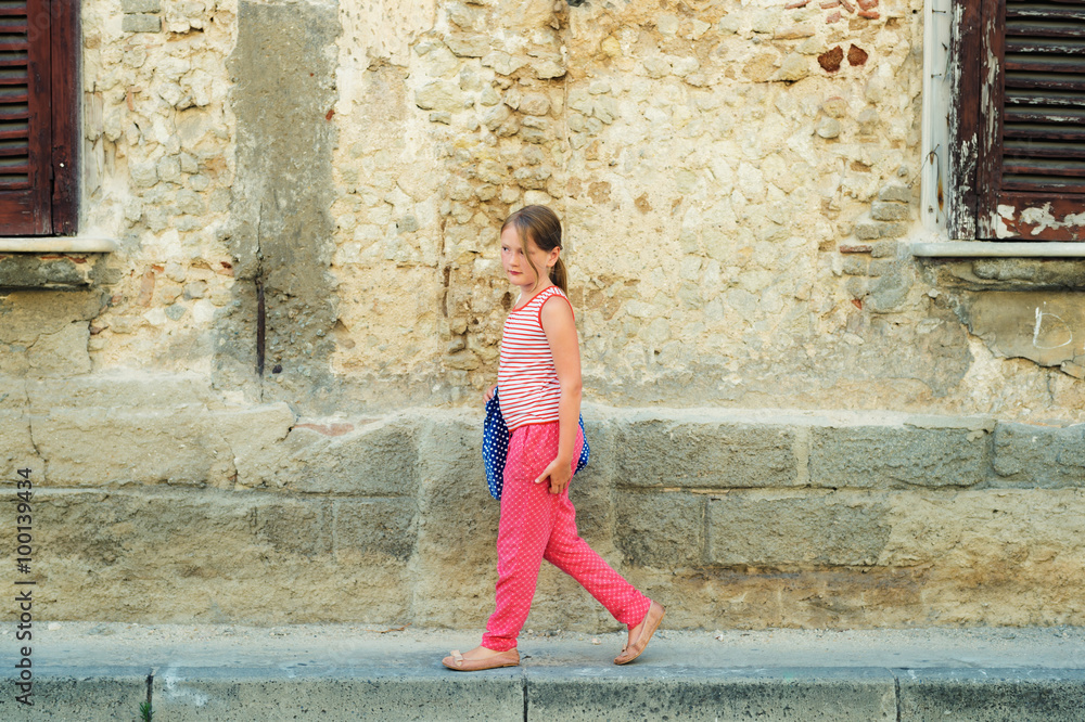 Outdoor fashion portrait of a pretty little girl, wearing red summer clothes, holding blue bag Outdoor fashion portrait of a pretty little girl, wearing red summer clothes, holding blue bag