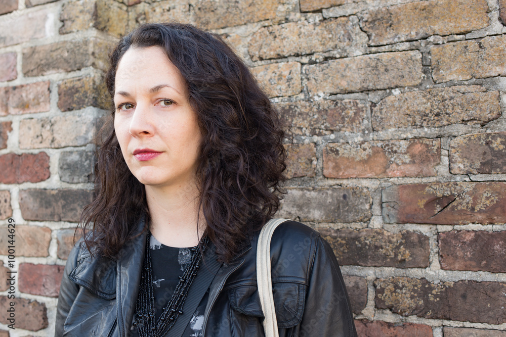 Serious woman in front of old brick wall Serious woman in front of old brick wall