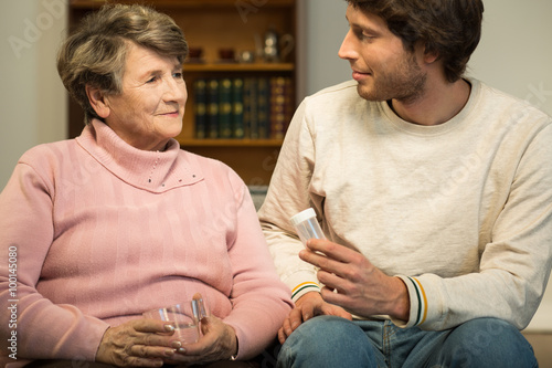 Man helping ill eledrly woman photo