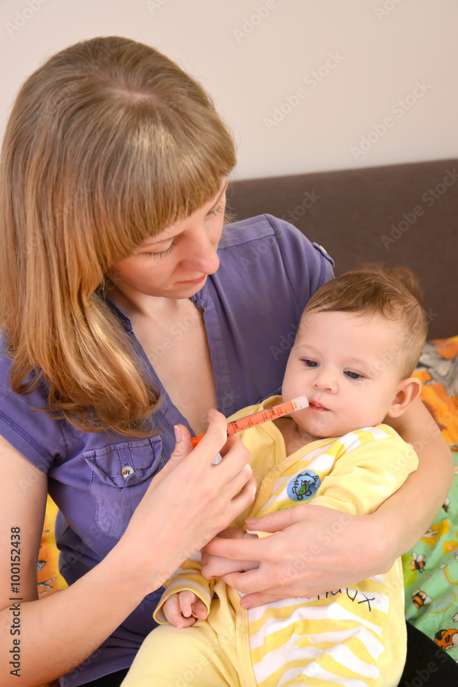 Mother gives to the sick baby medicine by means of the batcher. Mother gives to the sick baby medicine by means of the batcher.