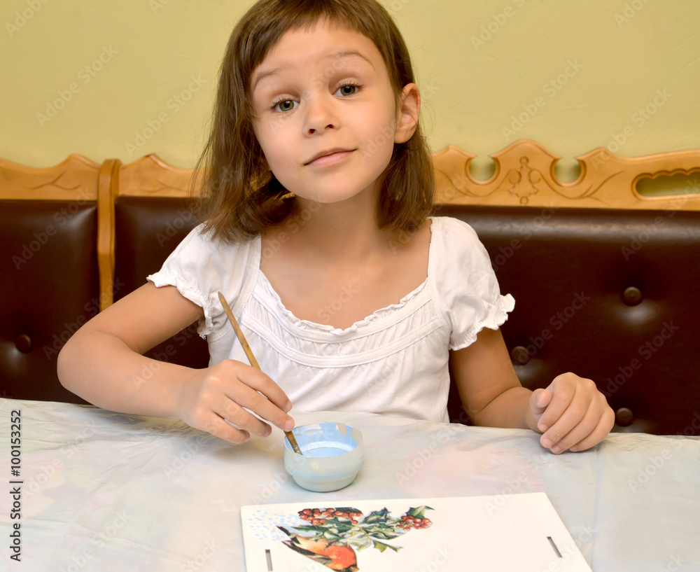 The little girl paints with paints a birds feeder The little girl paints with paints a birds feeder