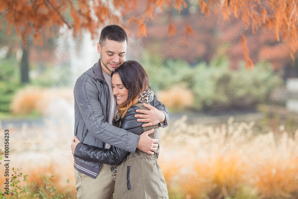 Happy young couple in love embracing while walking in a park Happy young couple in love embracing while walking in a park